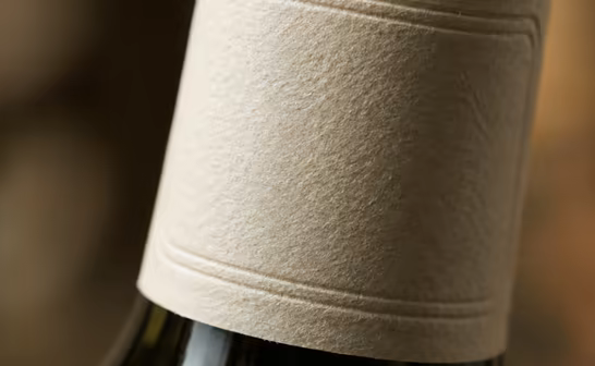 Close-up of an embossed paper label on a dark glass bottle
